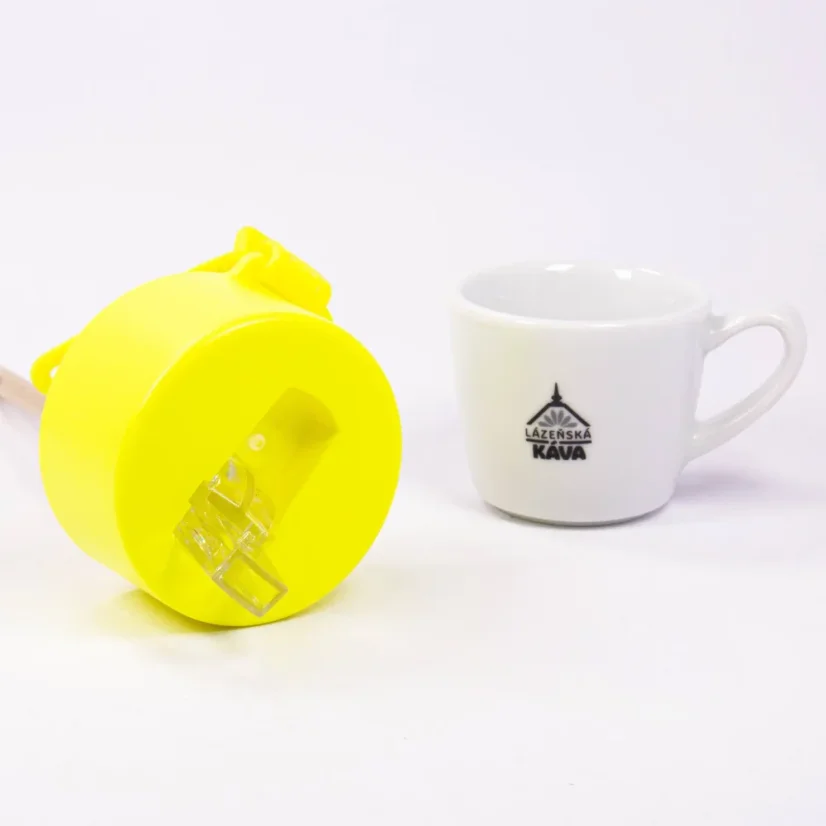 Detail of the drinking spout of a thermal bottle with coffee in the background.