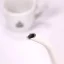 White electric kettle, detail on the spout with a coffee cup in the background.