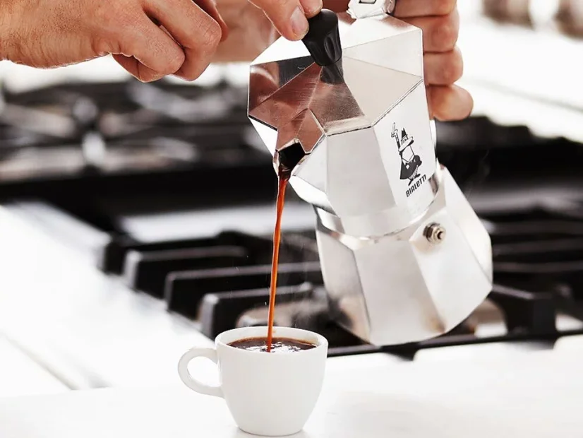 Mann gießt fertiges Espresso in eine Tasse.