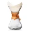 Chemex en verre avec poignée en bois, filtre en papier et lien en cuir.