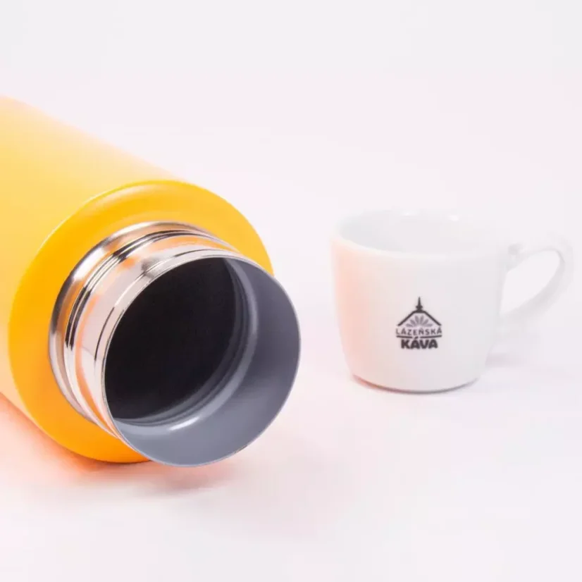 Detail na telo keramickej termosky s kávou v pozadí.