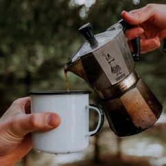 Verter el café preparado en una Bialetti Moka Express en una taza de lata.