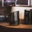 Nerezová kanvička od značky Barista a Co Dial In Milk Pitcher 420ml v tmavom prevedení v kompozícii s ďalšou kanvičkou.