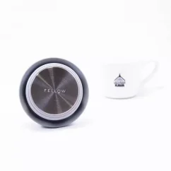 Detail of the underside of a thermal mug lid with coffee in the background