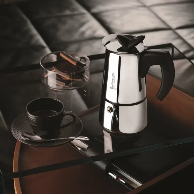 Bialetti Musa kettle next to a black cup.