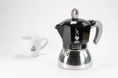 Aluminium Mokka Pot gëeegent fir Induktioun mat Logo vum Hiersteller - italienescher Firma Bialetti a Kompositioun mat enger Taass.