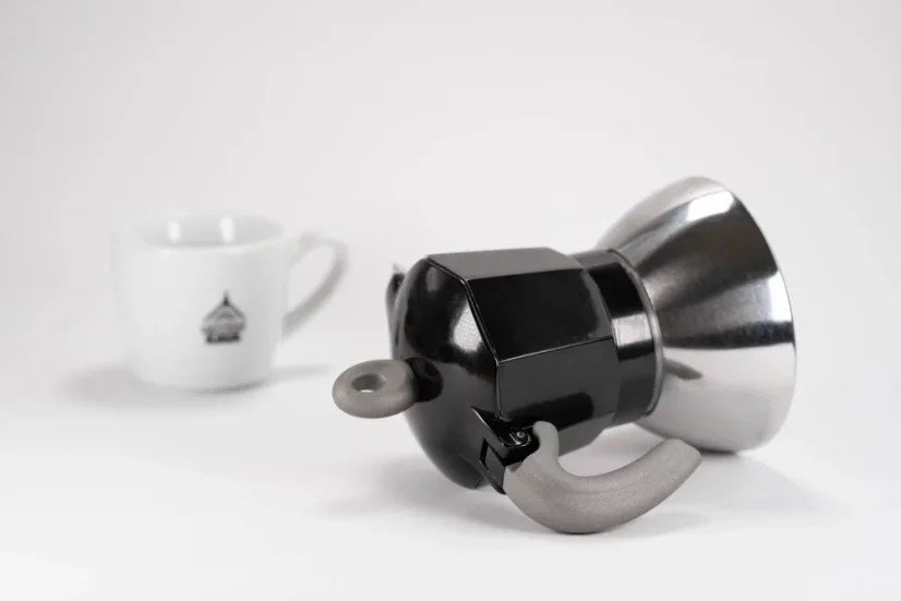 Practical handle of an aluminum Moka pot suitable for induction by the Italian brand Bialetti, composed with a cup bearing a logo.