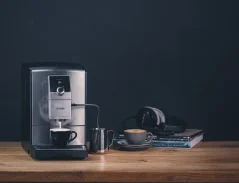 Cafetière argentée Nivona 799 avec préparation de cappuccino, posée sur une table. Cafetière argentée Nivona 799 avec préparation de cappuccino, posée sur une table.
