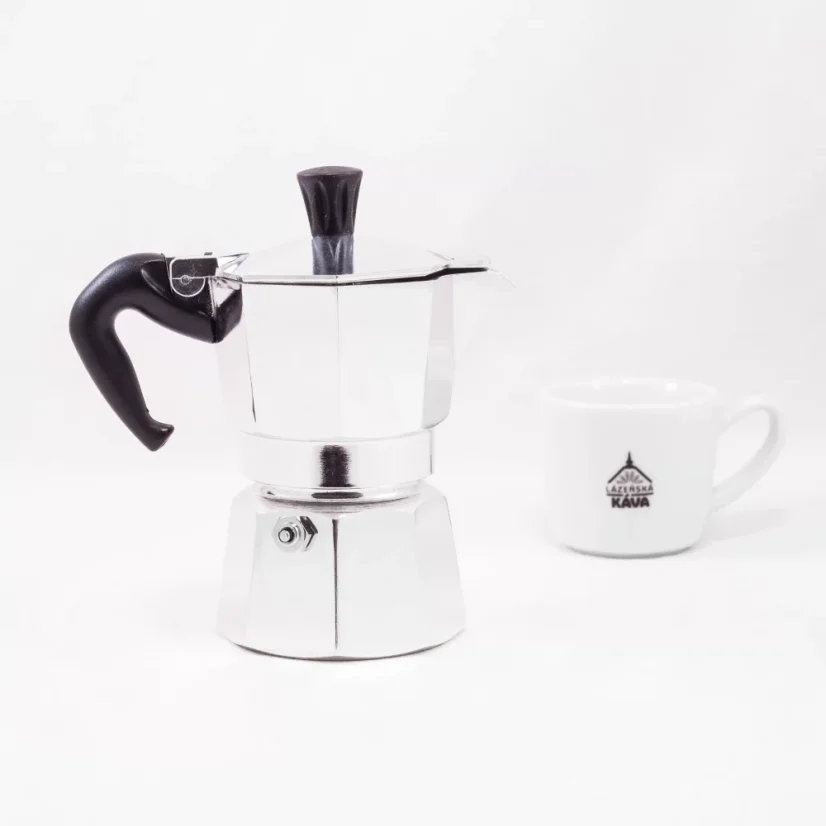 Silver Bialetti Moka Express pot for 2 cups on a white background with a cup of coffee