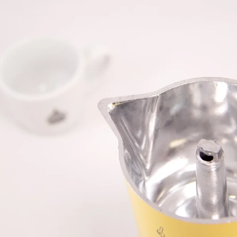 Détail du bec de la cafetière avec du café en arrière-plan.
