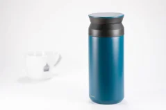 Türkise Edelstahl-Thermoflasche mit einem Volumen von 350 ml auf weißem Hintergrund mit einer Tasse Kaffee. Türkise Edelstahl-Thermoflasche mit einem Volumen von 350 ml auf weißem Hintergrund mit einer Tasse Kaffee.