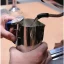 Whisking milk in a stainless steel jug with a thermometer by Rhinowares Whisking milk in a stainless steel jug with a thermometer by Rhinowares