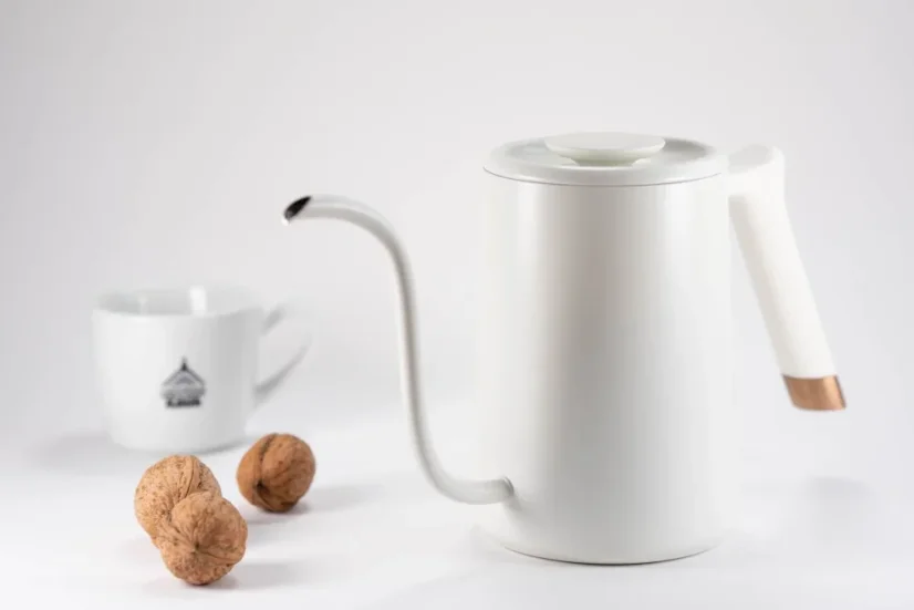 Electric kettle in white from Timemore Fish Pure Over, 0.7 liter capacity on a white background with a cup and walnuts.