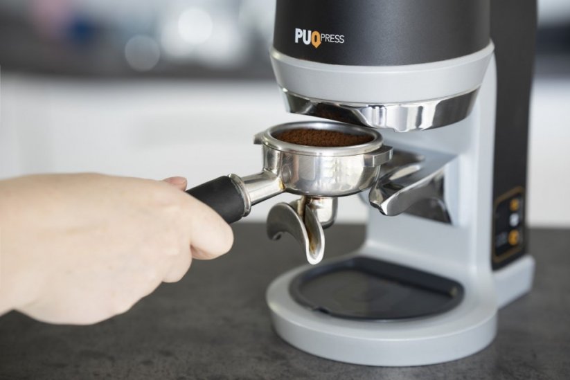 A kávéval töltött portafilter behelyezése a Puqpress Q1 készülékbe.