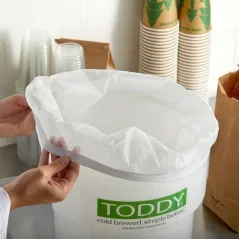 Inserting a paper filter into a plastic container for preparing Toddy Commercial cold brew.