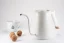 Electric kettle in white from Timemore Fish Pure Over, 0.7 liter capacity on a white background with a cup and walnuts.