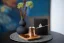 Kupferne Džezva zur Zubereitung von türkischem Kaffee mit frisch gemahlenem Kaffee auf einem Holztablett, Hintergrund ergänzt durch eine Schachtel mit Kaffeebohnen und einer schwarzen Vase gefüllt mit Wiesenblumen.