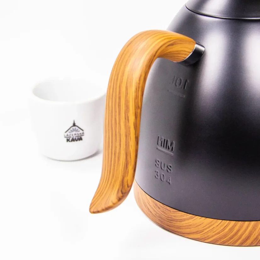 Vue détaillée de la poignée d'une bouilloire Brewista en finition noir mat avec des éléments en bois, offrant une manipulation confortable, avec une tasse en arrière-plan.