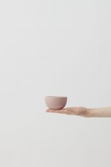 Una taza de café Aoomi en la palma de la mano.