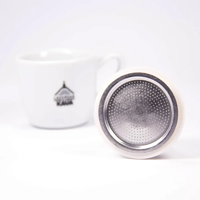 Espresso cup with logo next to a spare seal and filter for a Bialetti Moka pot.