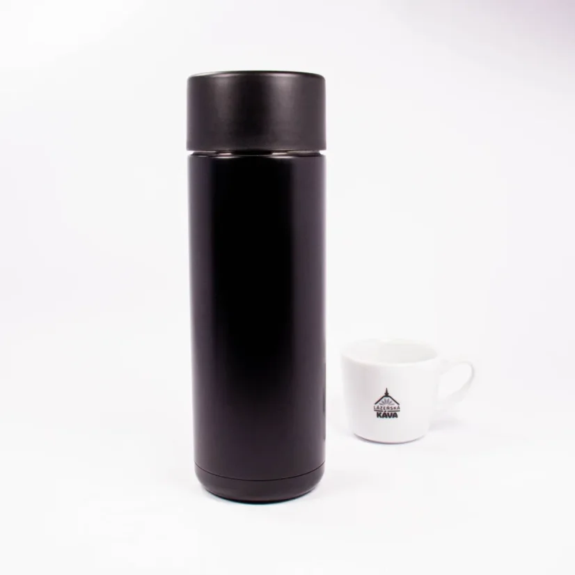 Keramická termoska zo zadnej strany s kávou v pozadí.