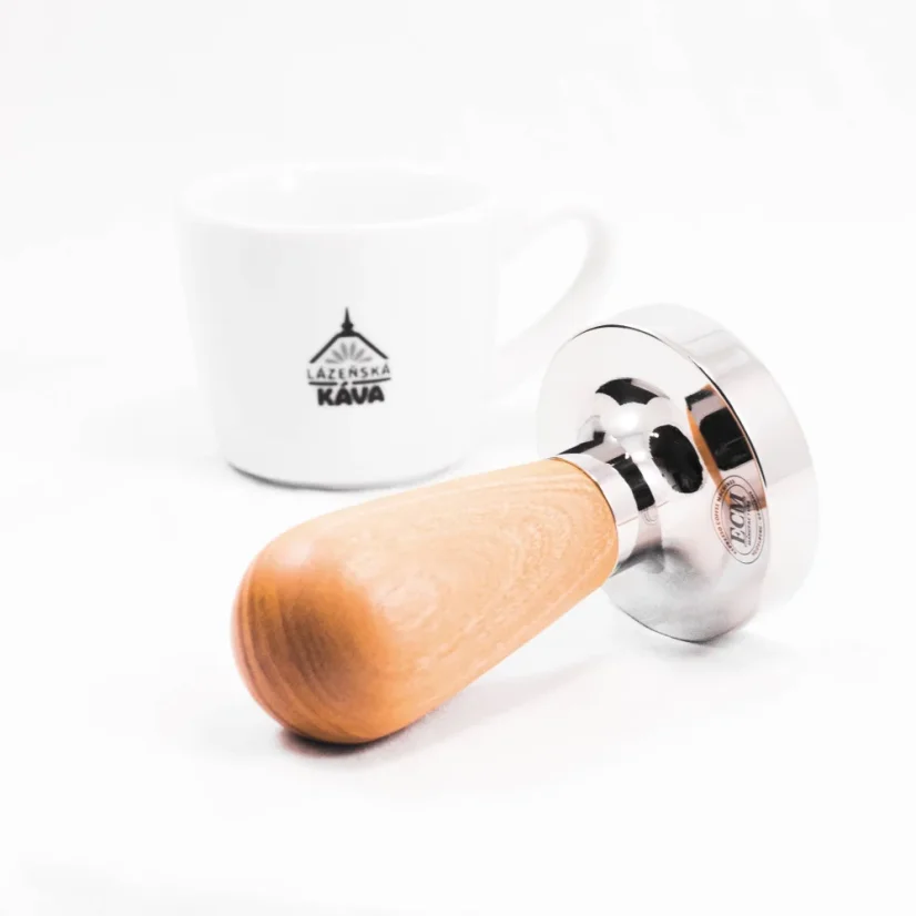 Tamper with an olive wood handle, coffee in the background.