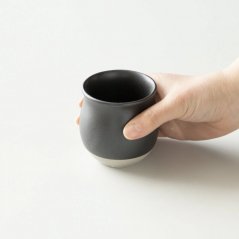 Schwarzer Becher für Filterkaffee in der Hand.