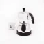 Silver Bialetti Moka Timer coffee maker for 3 cups, rear view, with a cup of coffee in the background.