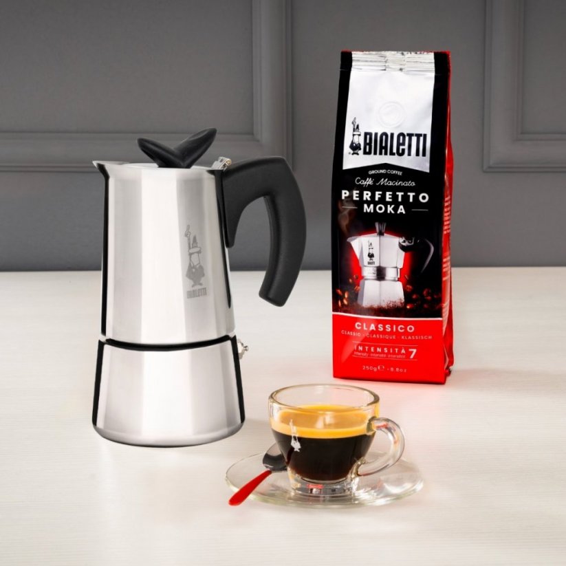 Coffee prepared in a Bialetti Musa pot, served in a transparent cup. Bialetti Musa pot and coffee beans in the background.