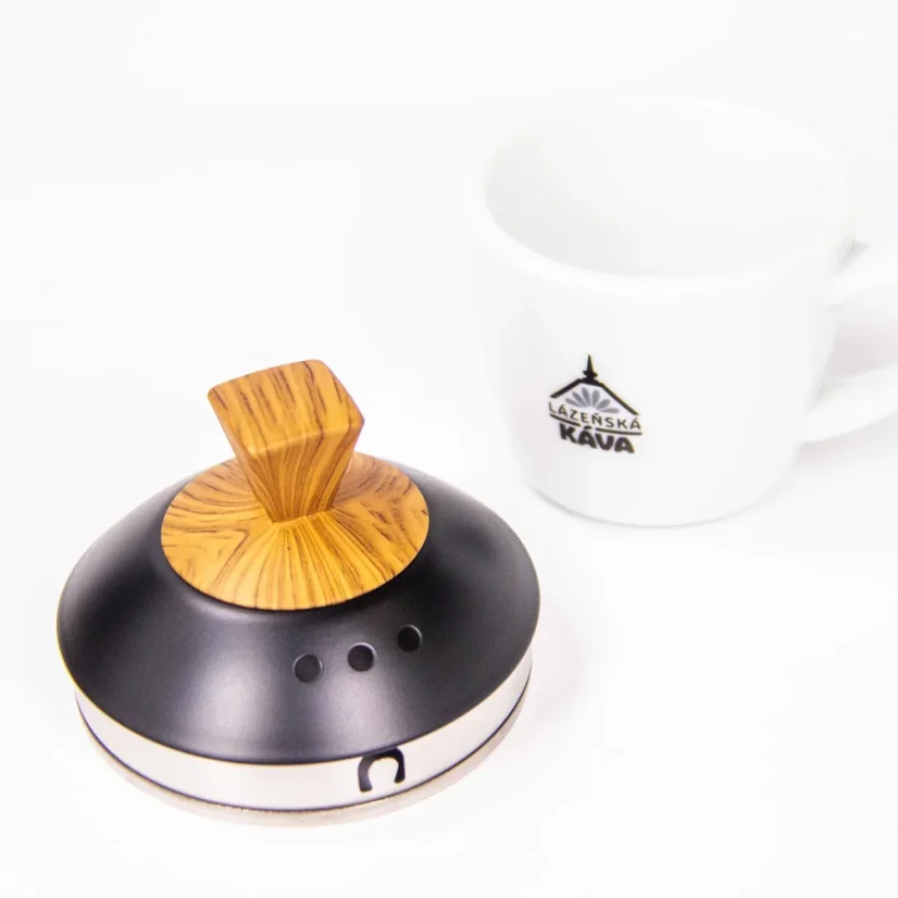 Couvercle d'une élégante bouilloire mate noire Brewista avec des éléments en bois à côté de notre tasse avec logo.