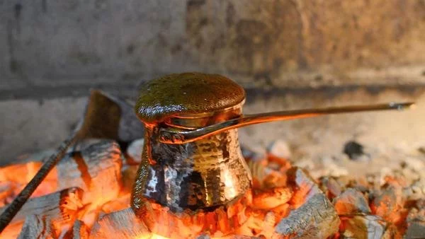Vorbereitung echten türkischen Kaffees in einem Kupfer-Ibrik über einem lodernden Feuer.