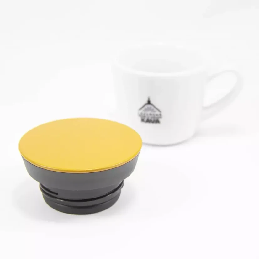 Yellow lid for the Kino Travel Tumbler Coyote 500ml with a white coffee cup in the background