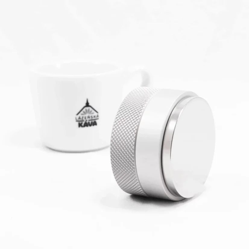 Detail of a coffee tamper with coffee in the background.