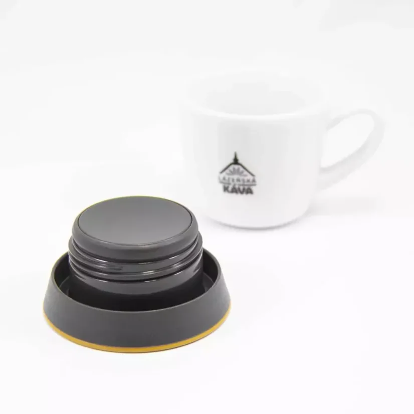 Black lid of a yellow Kinto Travel Tumbler Coyote 500ml with a cup of coffee on a white background