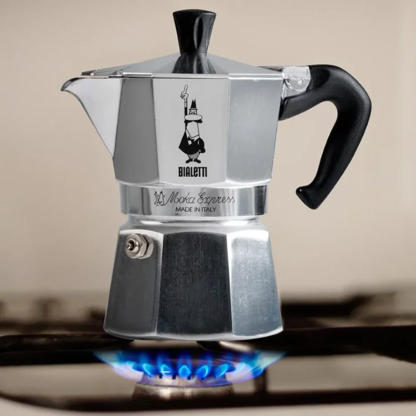 Cafetera Bialetti Moka Express plateada sobre una estufa de gas.