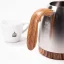 Silver electric kettle, detail of a wooden handle on a white background with a cup of spa coffee