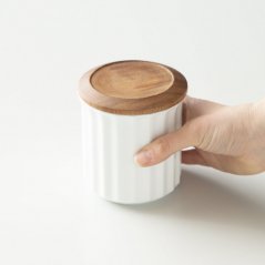 Origami porcelain coffee jar in white colour held in hands.