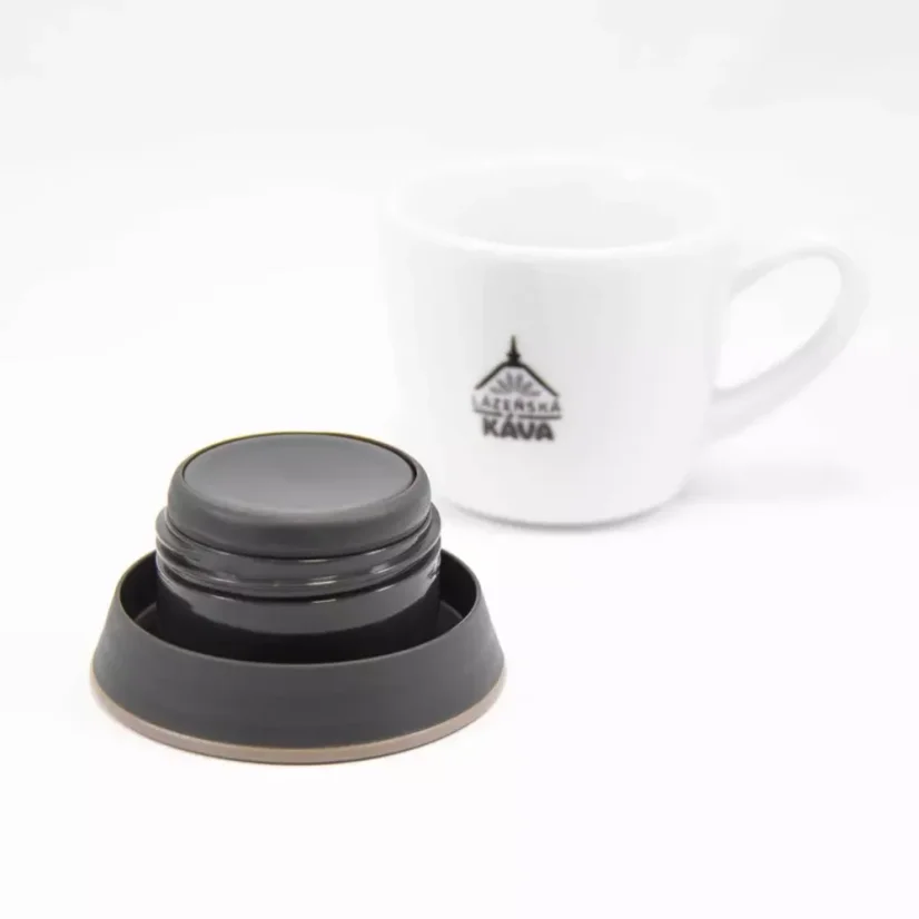 Détail de l'intérieur du couvercle de la tasse isotherme Kinto Travel Khaki 350 ml, avec en arrière-plan une tasse en porcelaine décorée.