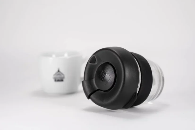 Sklenený termohrnček s čiernym viečkom a čiernym gumeným držiakom o objeme 227 ml s šálkou kávy, detail na viečko