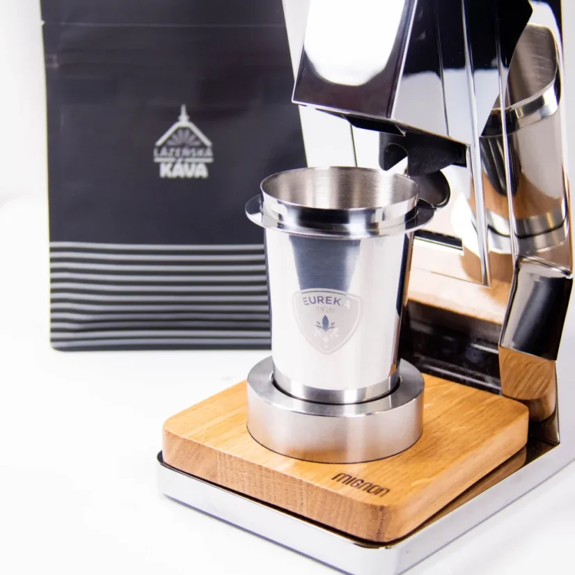 Stainless steel cup for ground coffee, positioned under the Eureka grinder.