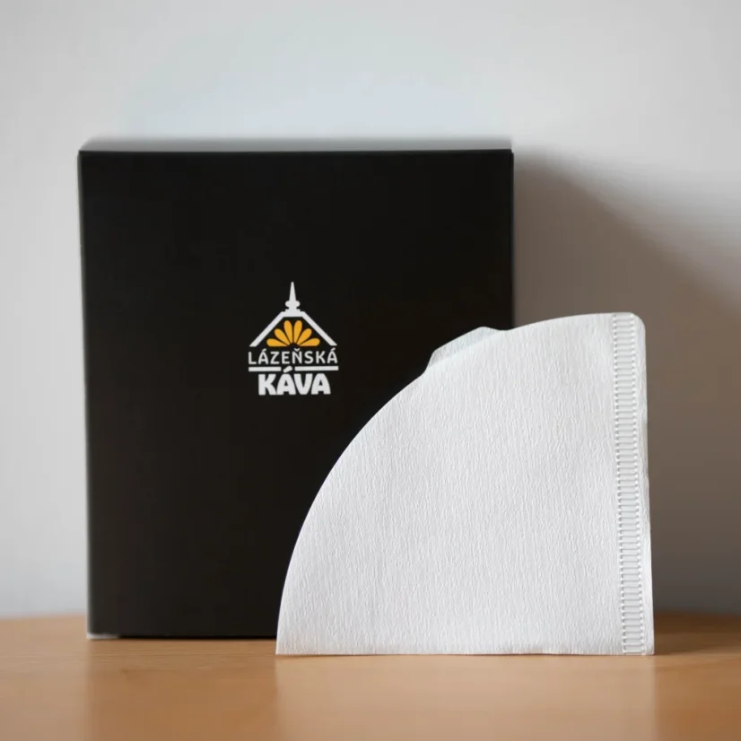 White paper filters on a wooden table and a black box with a logo on a white background