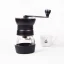 Black Hario Skerton Pro manual coffee grinder on a white background with a cup of coffee