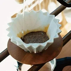 White origami dripper during the preparation of filtered coffee.