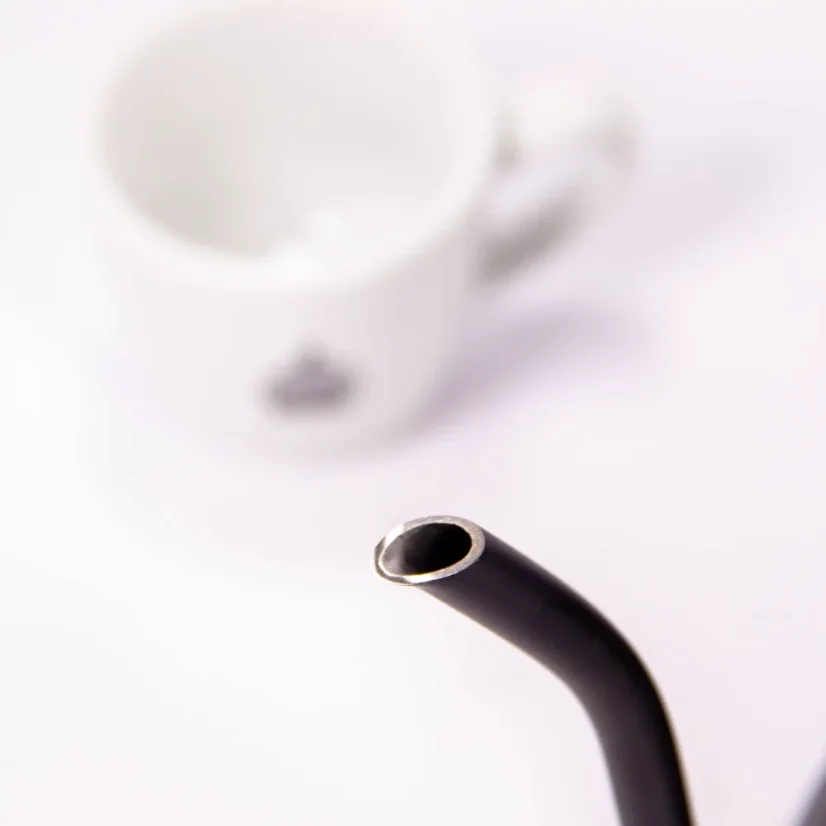 Black electric kettle on a white background with a cup of coffee, detail on the goose neck spout