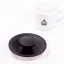 Detail of the lid of a black electric kettle on a white background with a cup of coffee