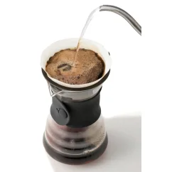 Decantador de goteo Hario V60 de vidrio con mango de cuero negro durante la preparación del café.