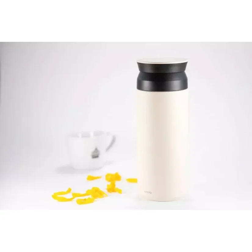 Gourde thermique blanche en acier inoxydable de 500 ml sur un fond blanc avec une tasse de café et des pétales jaunes.