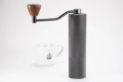 High-quality Timemore coffee grinder with a sturdy aluminum body and wooden handle in the background with our coffee cup.