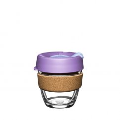 Tazza da caffè in vetro con coperchio viola e supporto in sughero.