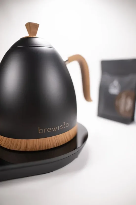 Bouilloire électrique élégante Brewista sur socle en finition noir mat avec poignée élégante et possibilité de régulation de température, entourée de notre café torréfié.